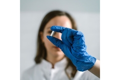 Image Person in a white coat holding up a supplement
